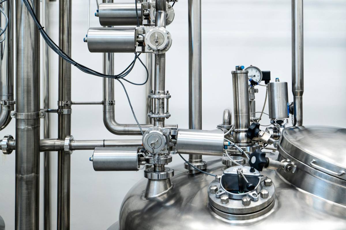 Close-up of a stainless steel process vessel with pneumatic valve actuators, pipework and a pressure gauge
