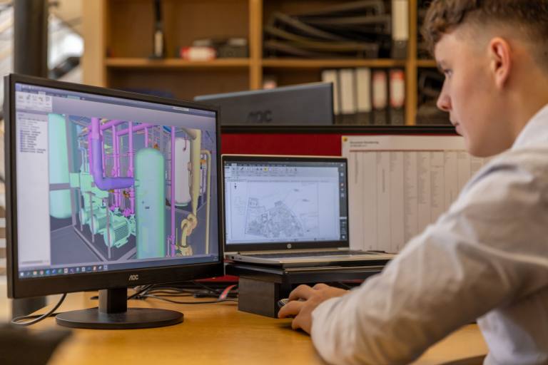 SENZAIT 3D Design — an engineer models a process skid in CAD on two monitors: tanks, pipework and supports in three dimensions.