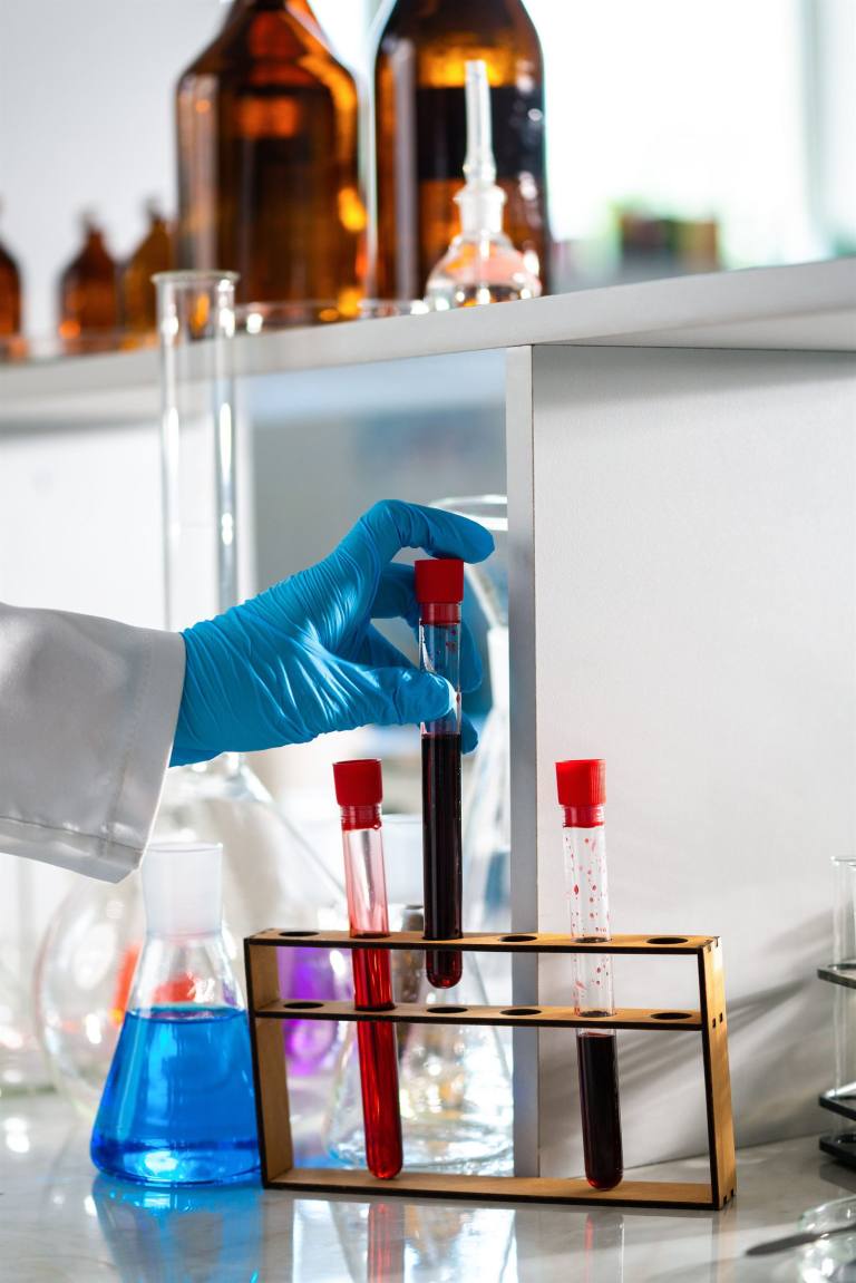 SENZAIT Applied research — test tubes standing in a wooden rack on a laboratory bench.