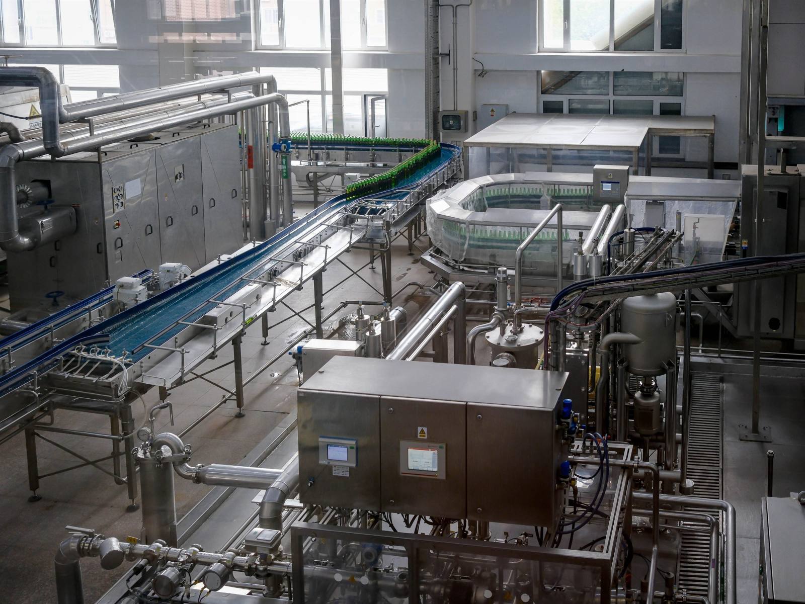 SENZAIT Industries served — interior of a modern beverage bottling plant, with filled bottles on a conveyor.
