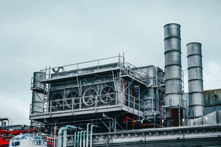 SENZAIT Mechanical projects — a steel plant structure with access platforms, ladders, cooling fans and two stacks against an overcast sky.