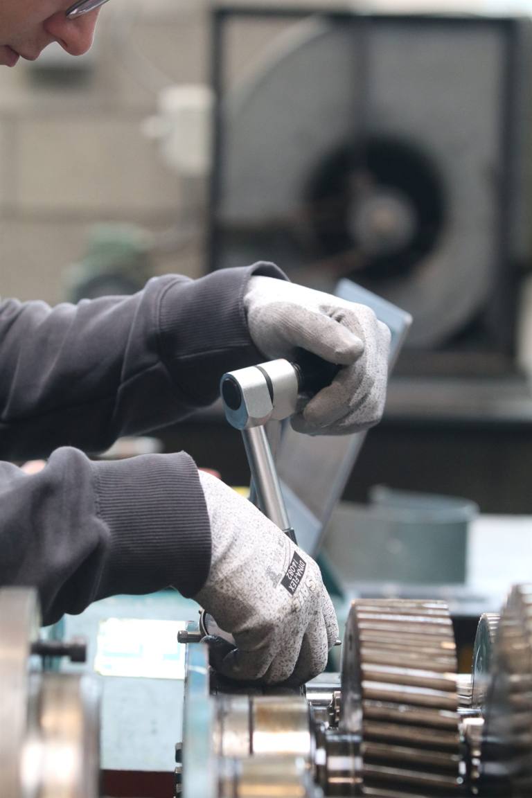 SENZAIT Prototype development — a person shaping a workpiece with a hand tool at a workshop bench.