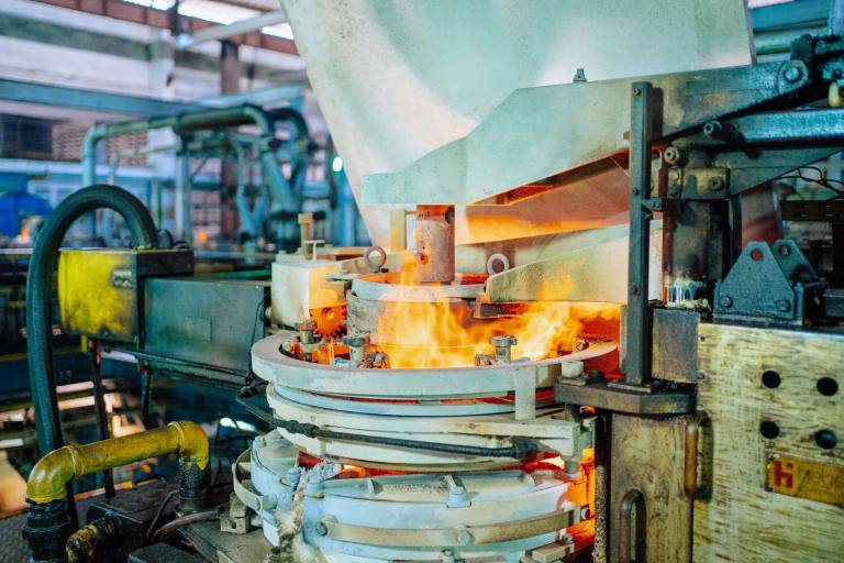 SENZAIT SEMWOF — a working industrial furnace with molten glass pouring from the feeder, the kind of high-temperature process the emulsion fuel is made for.