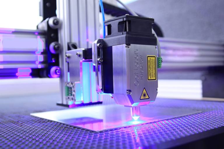 SENZAIT Sheet metal fabrication — a CNC laser cutting head working across sheet metal.
