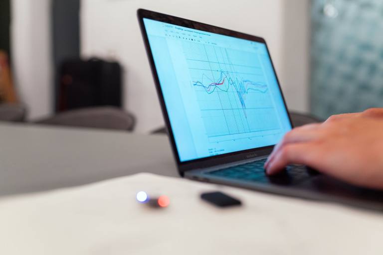 SENZAIT Simulation — an engineer reads a plotted result curve on a laptop, checking a model against the numbers before anything is built.